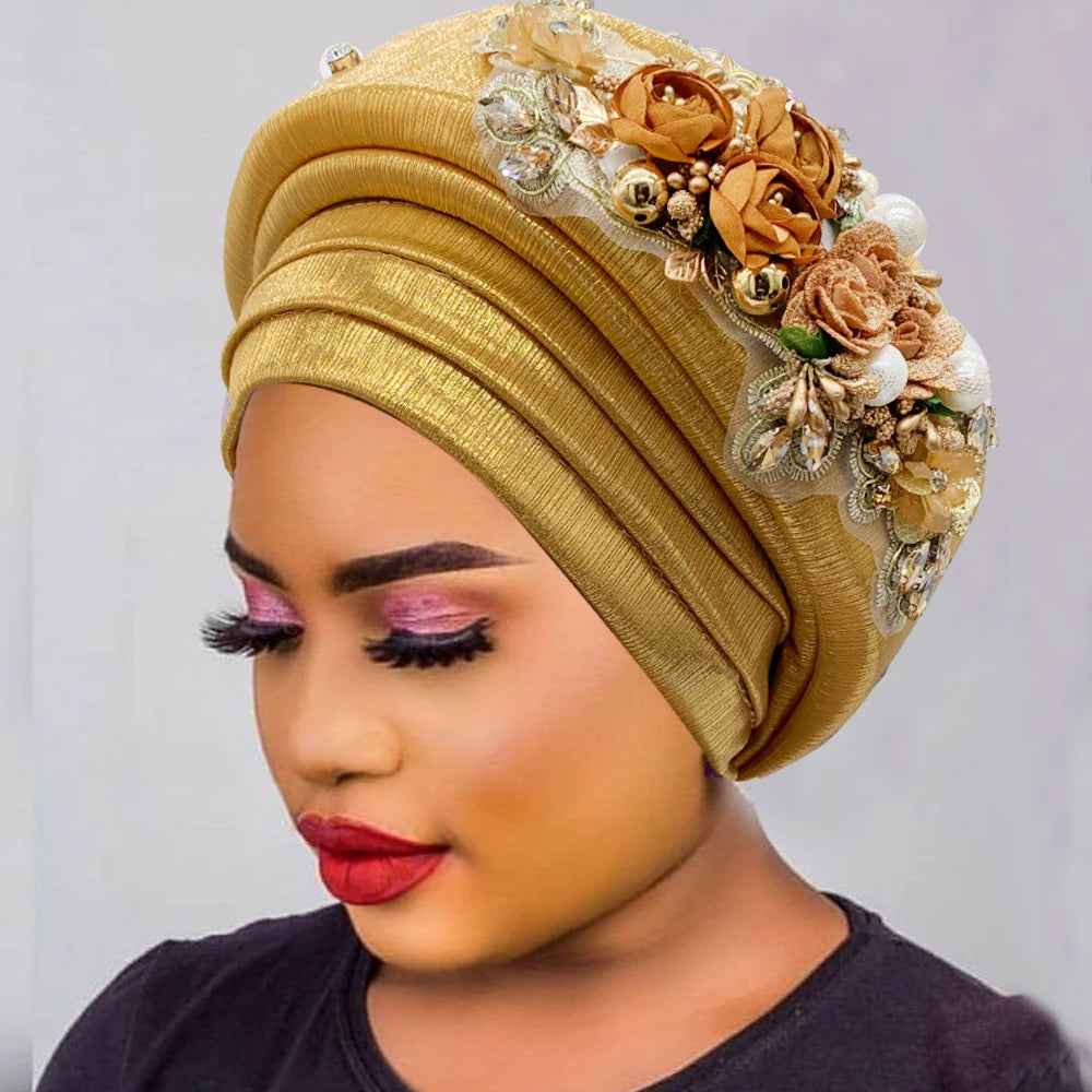 Woman wearing a gold auto gele with a flower and bead bouquet detail