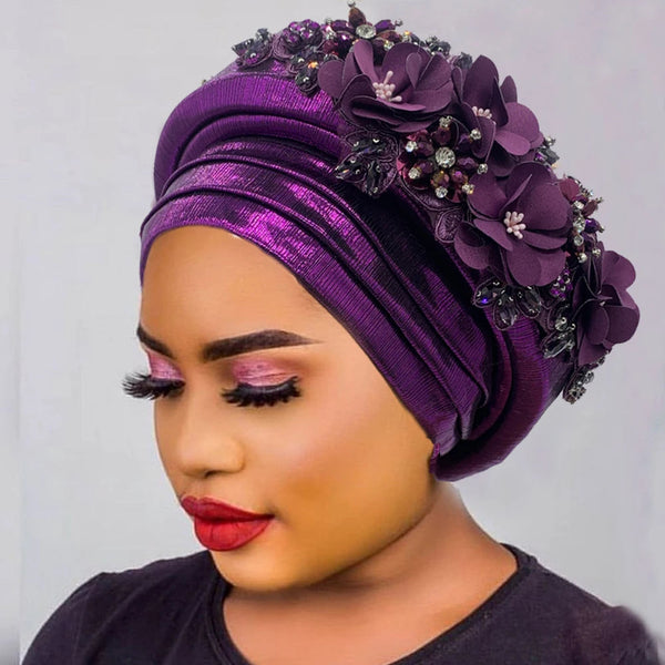 Woman wearing a purple gele with a floral bouquet detail on the crown